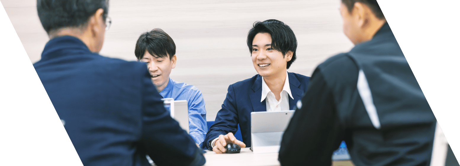 男性スタッフ4名がPCを見ながら笑顔で打ち合わせをしている写真