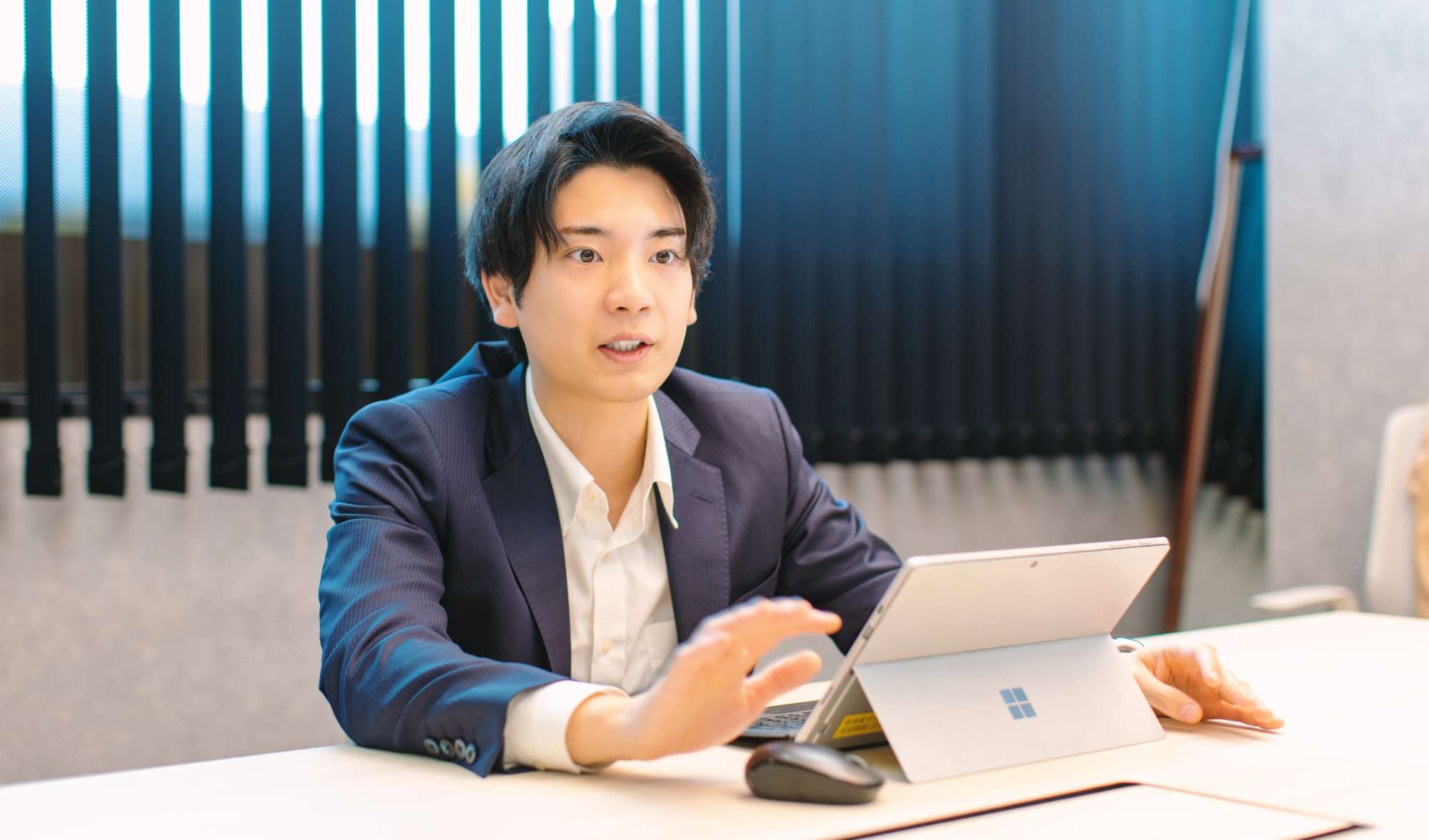 PCの前で身振り手振りしながら語る田中さんの写真