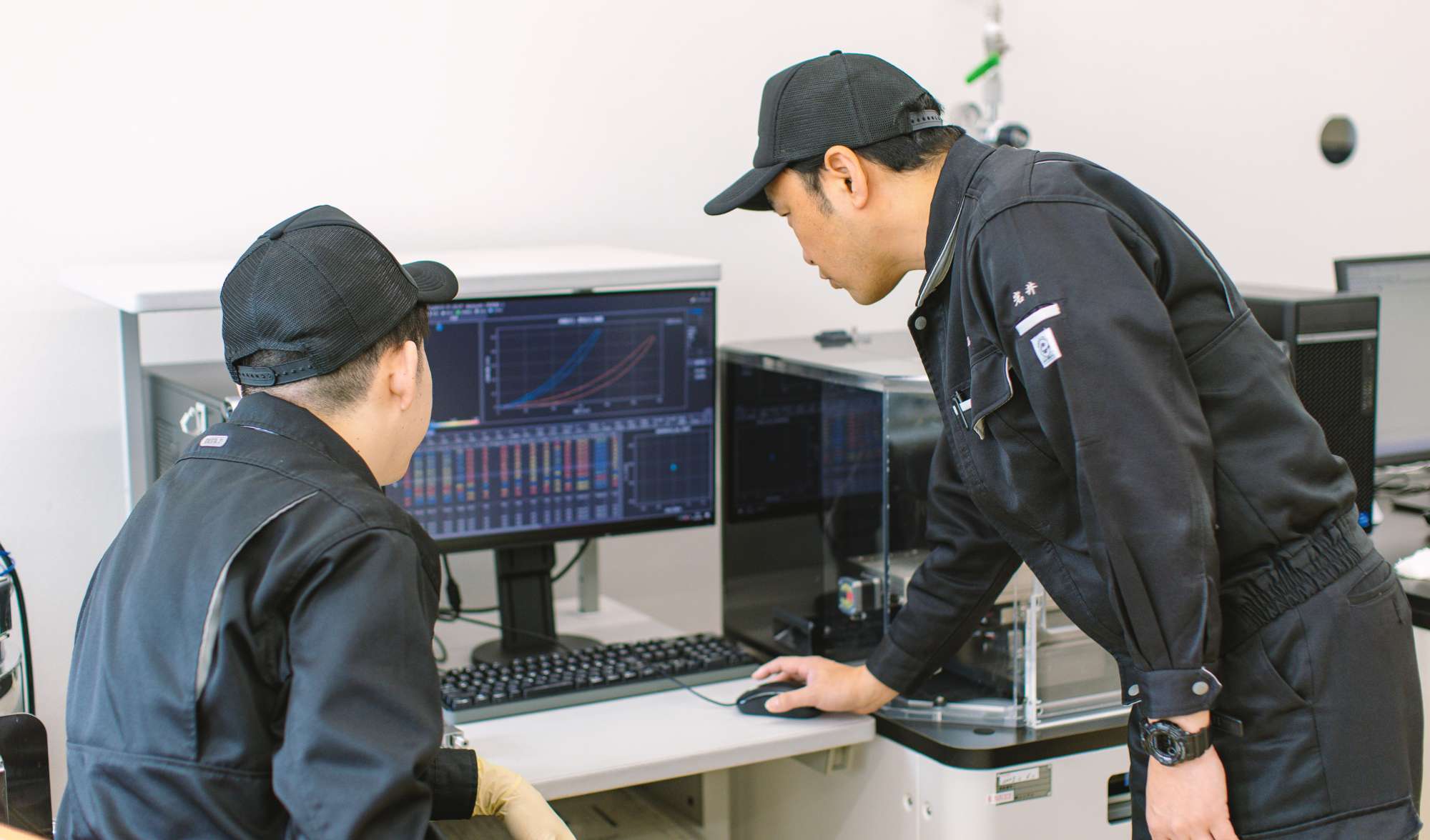PCを見ながら同僚と二人で相談しながら話す中西さんの写真