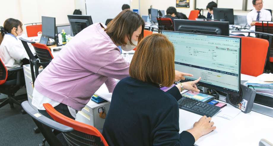 PCを指差して何かを確認している購買調達部門のスタッフの写真